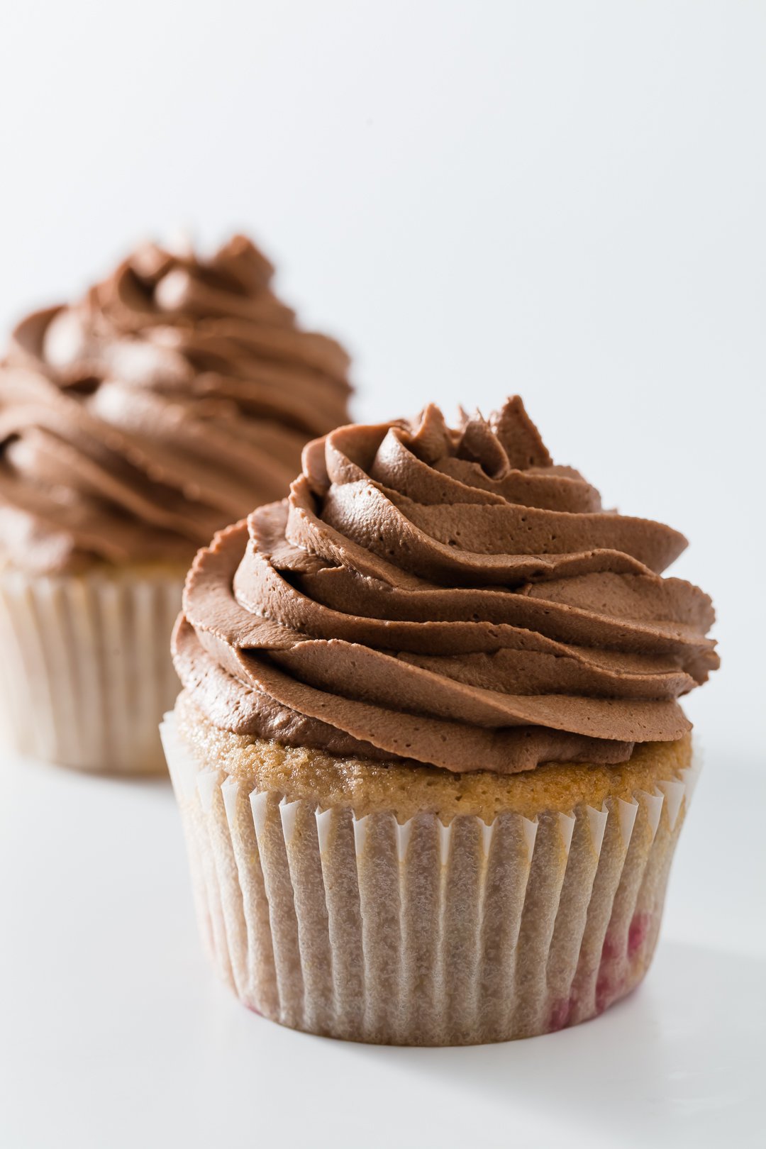 Two cupcakes topped with chocolate whipped cream