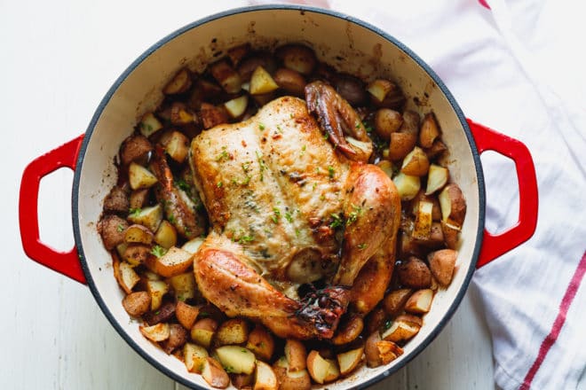 Whole roasted chicken with potatoes on a baking dish