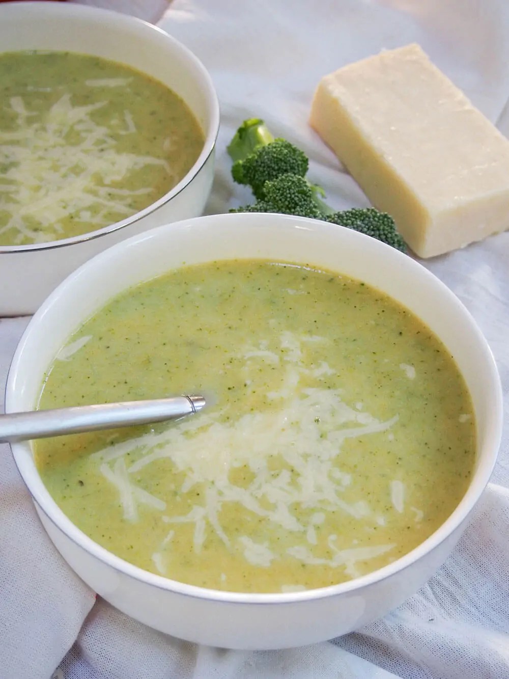 Pumpkin broccoli soup with cheddar with spoon in bowl