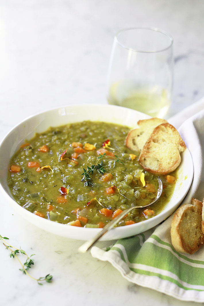 A bowl of vegetarian slow cooker split pea soup with sliced baguette. 