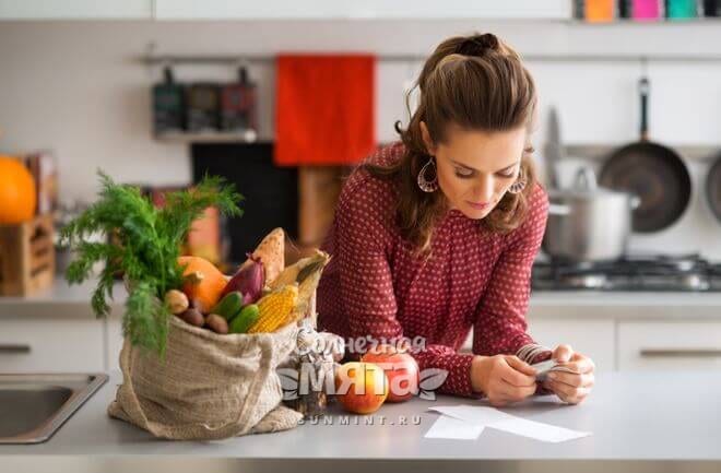 Женщина изучает кассовый чек после покупки продуктов, фото