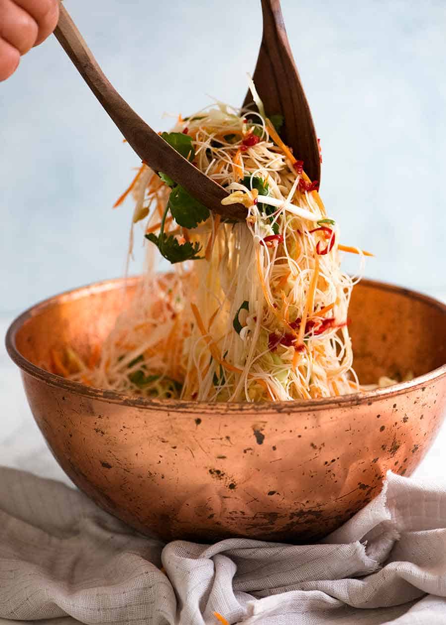 Tossing Vermicelli Noodle Salad in a rustic copper bowl