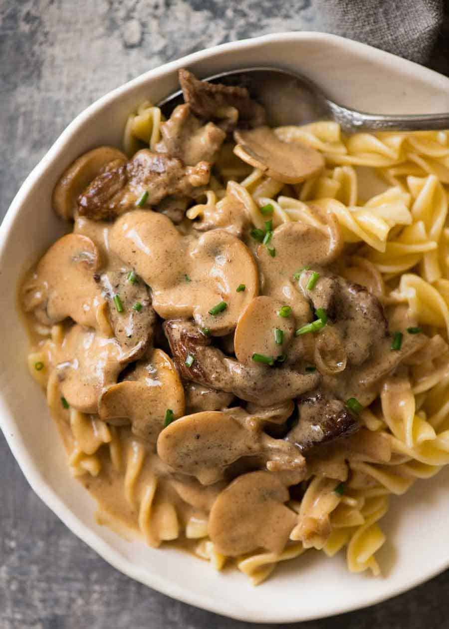 Beef Stroganoff in a rustic white bowl over noodles